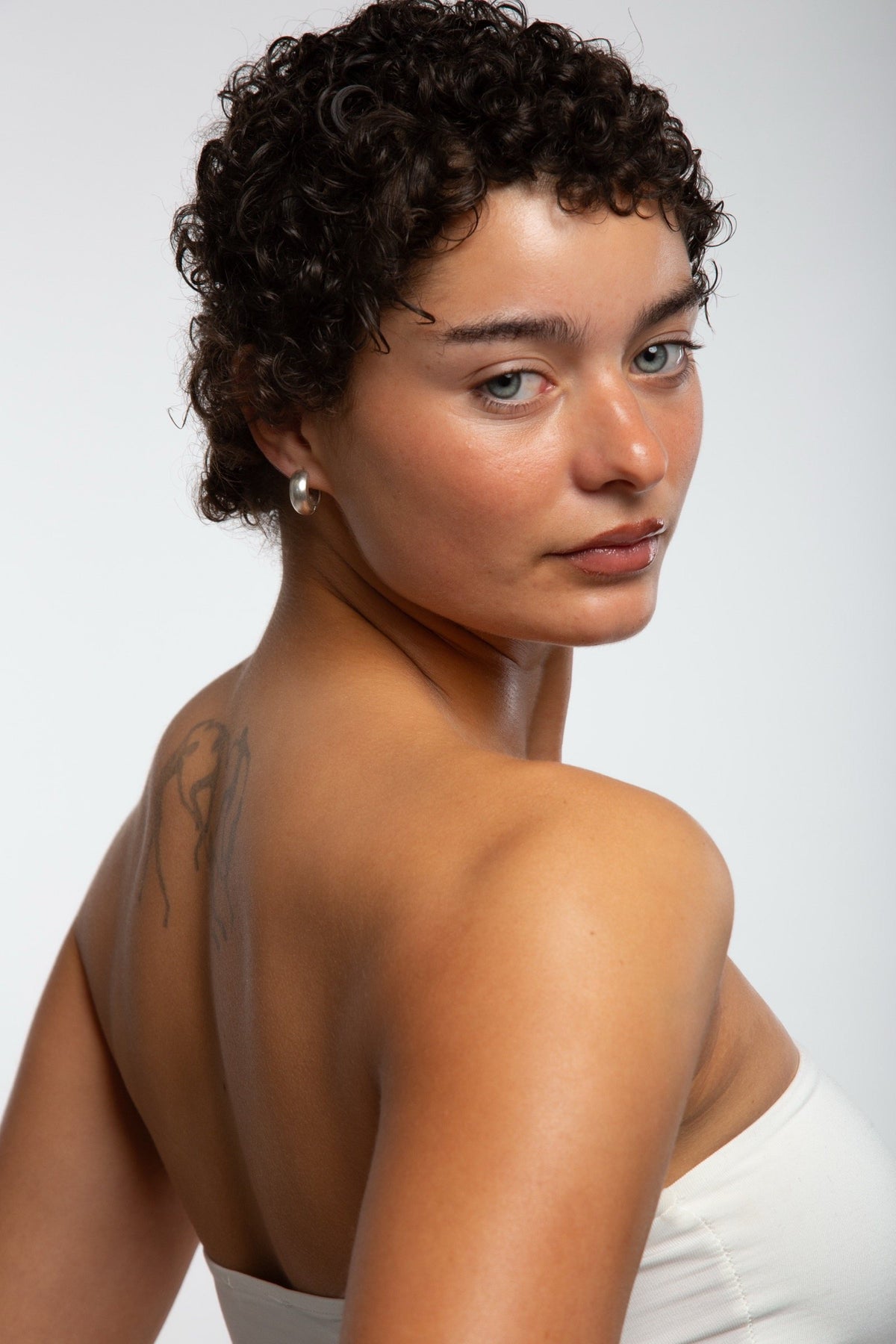 Portret van model met kort krulhaar, van opzij