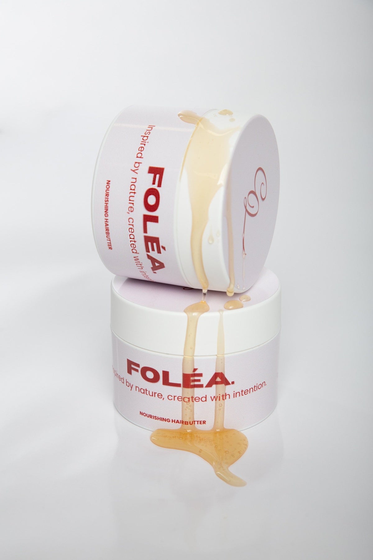 Gouden olie die over twee potten FOLÉA Nourishing hairbutter loopt